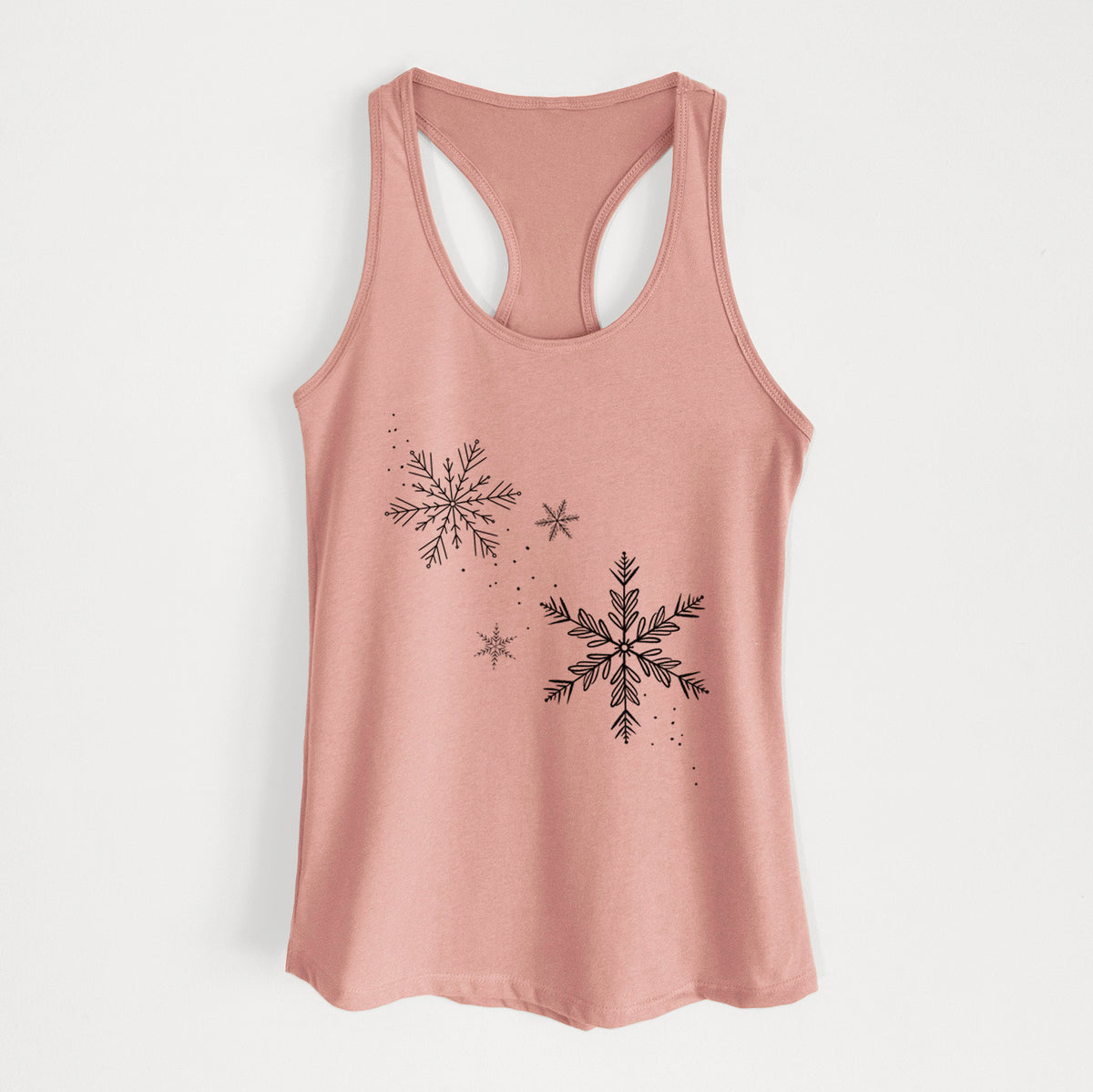 Desert pink women's racerback tank top laid flat, printed with delicate snowflakes of different sizes falling.