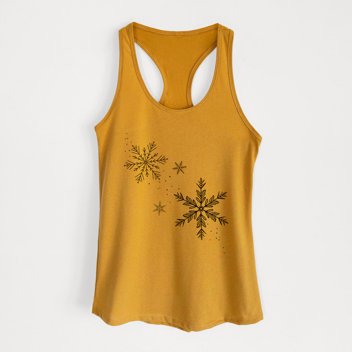 Gold women's racerback tank top laid flat, printed with delicate snowflakes of different sizes falling.