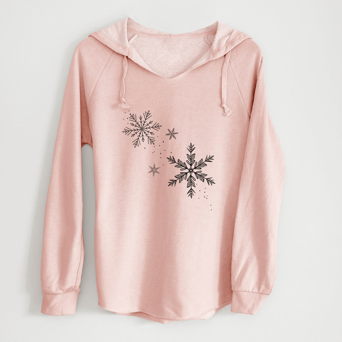 Blush pink women's Cali Wave hooded sweatshirt laid flat, printed with delicate snowflakes of different sizes falling.