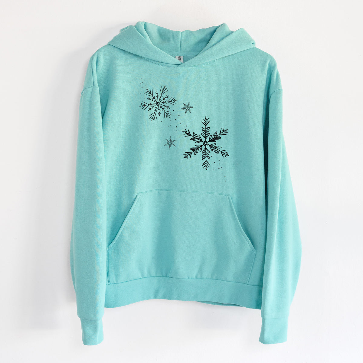 Falling Snowflakes - Statement Midweight Hoodie in Seafoam, hanging on a white wall, with a front kangaroo pocket and no drawcords.