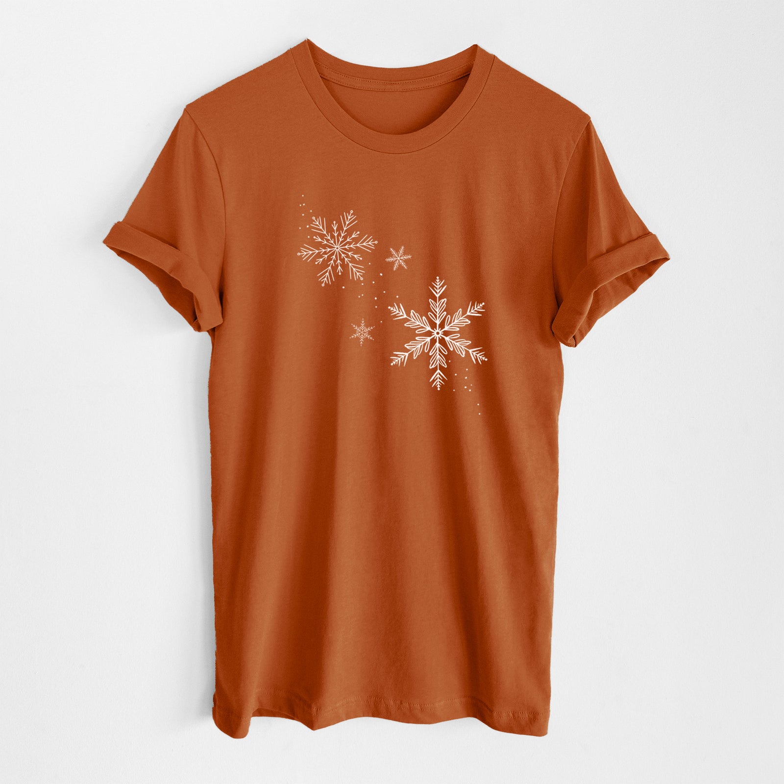 Autumn lightweight cotton t-shirt laid flat, printed with delicate white snowflakes of different sizes falling.