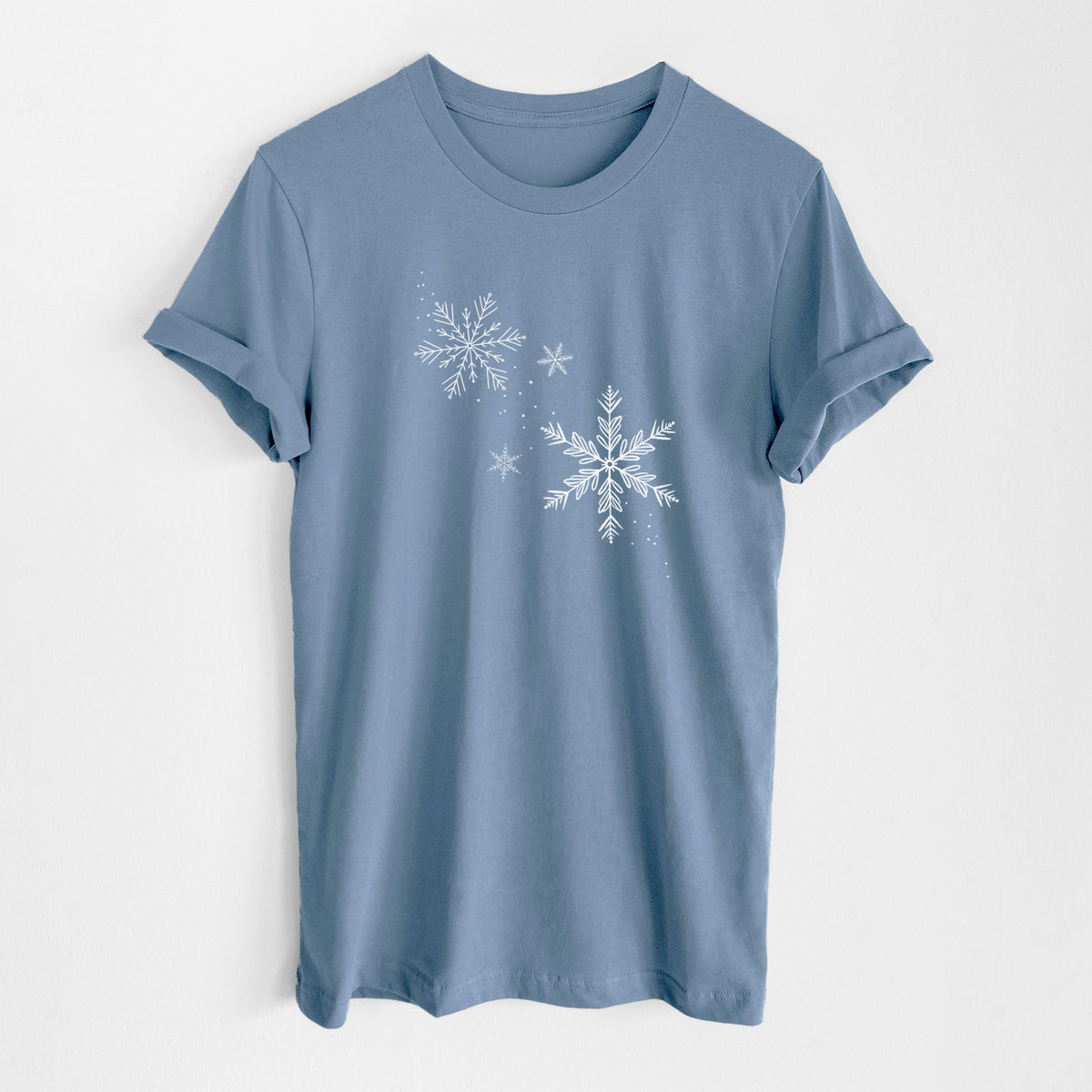 Steel blue lightweight cotton t-shirt laid flat, printed with delicate white snowflakes of different sizes falling.