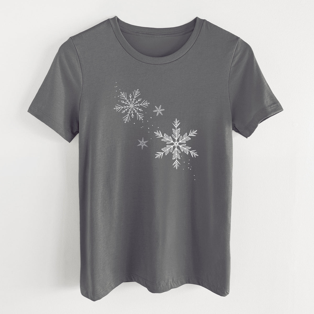 Asphalt women's relaxed fit cotton t-shirt laid flat, printed with delicate white snowflakes of different sizes falling.
