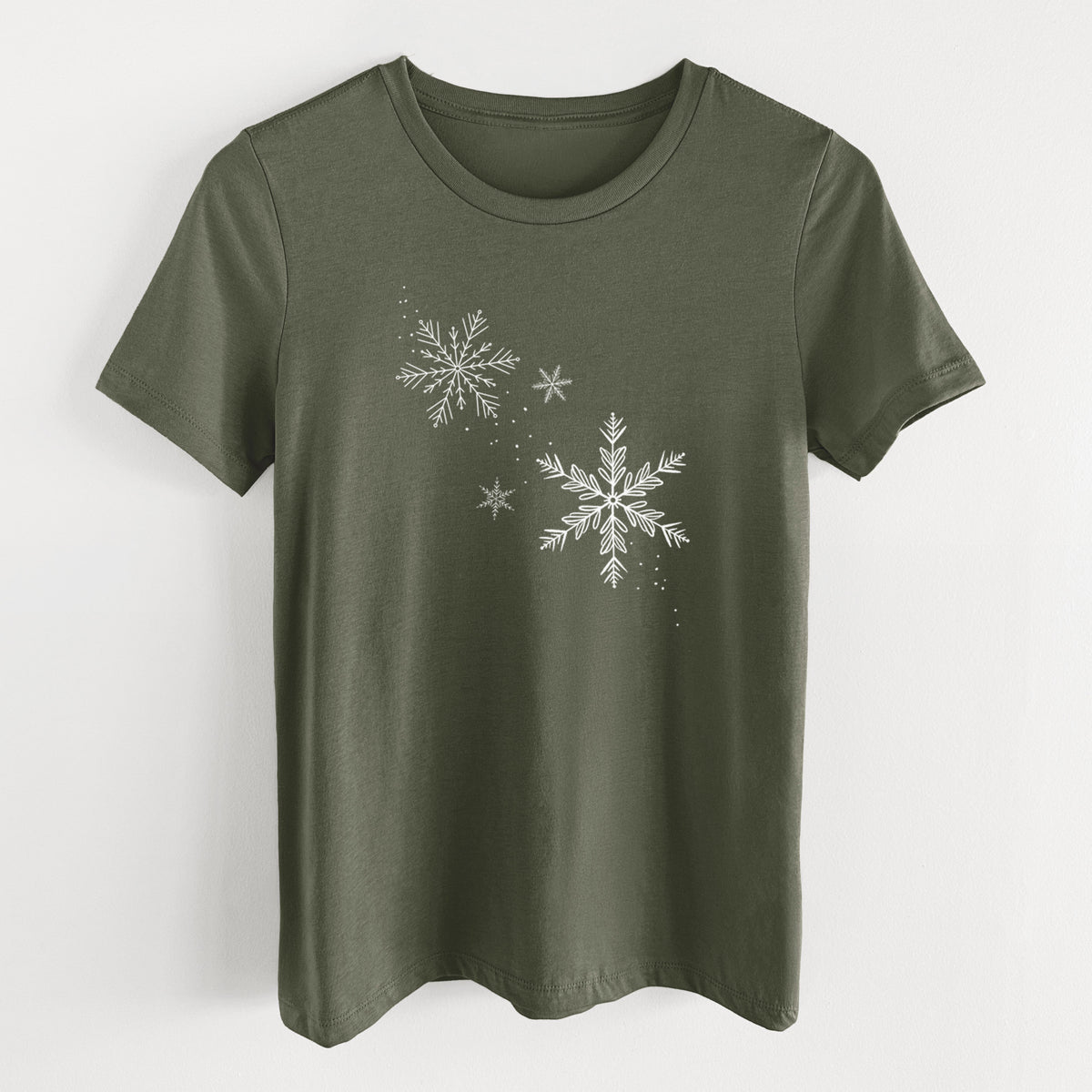 Military green women's relaxed fit cotton t-shirt laid flat, printed with delicate white snowflakes of different sizes falling.