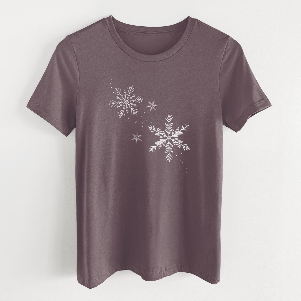 Purple storm women's relaxed fit cotton t-shirt laid flat, printed with delicate white snowflakes of different sizes falling.