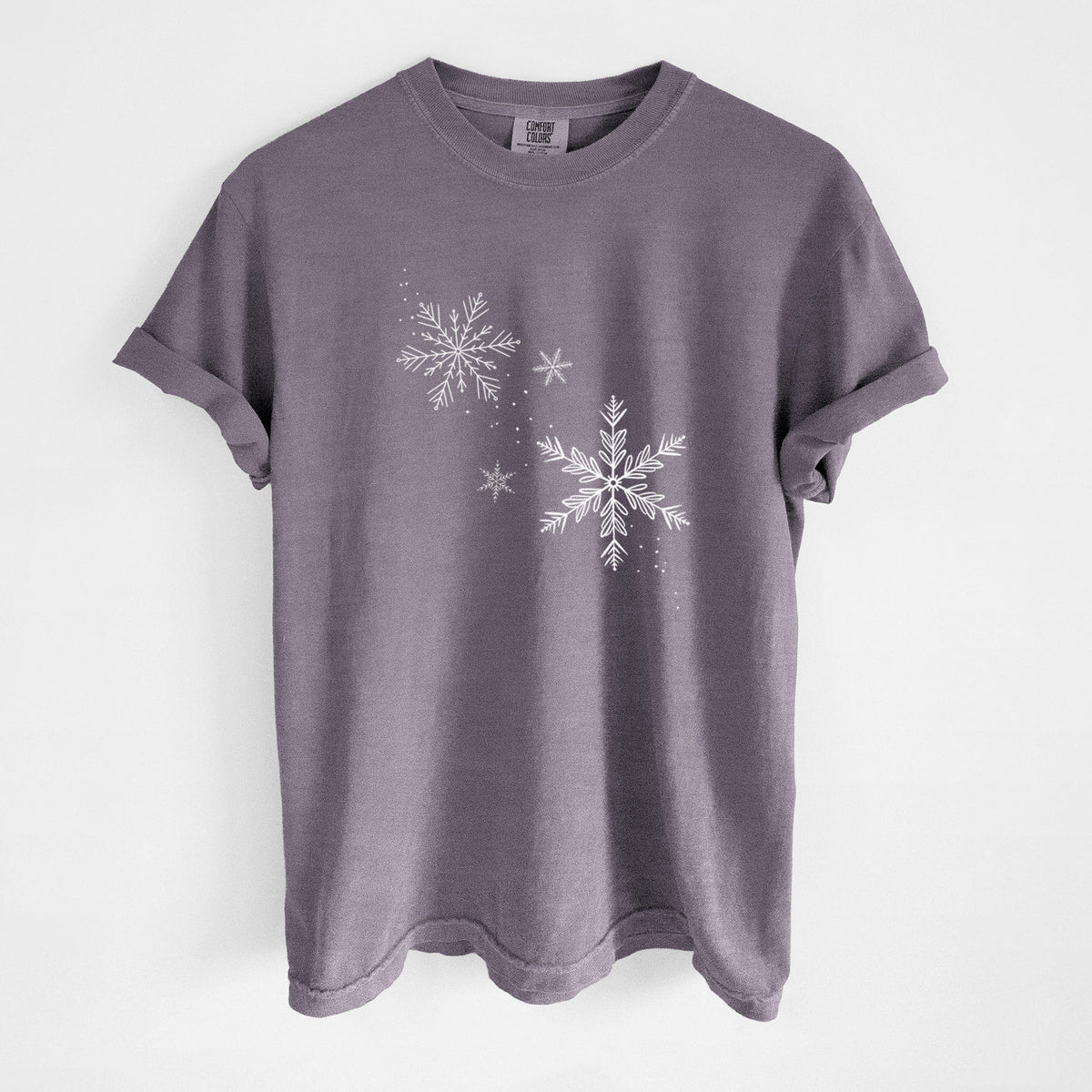 Wine red Comfort Colors t-shirt laid flat, printed with delicate white snowflakes of different sizes falling.