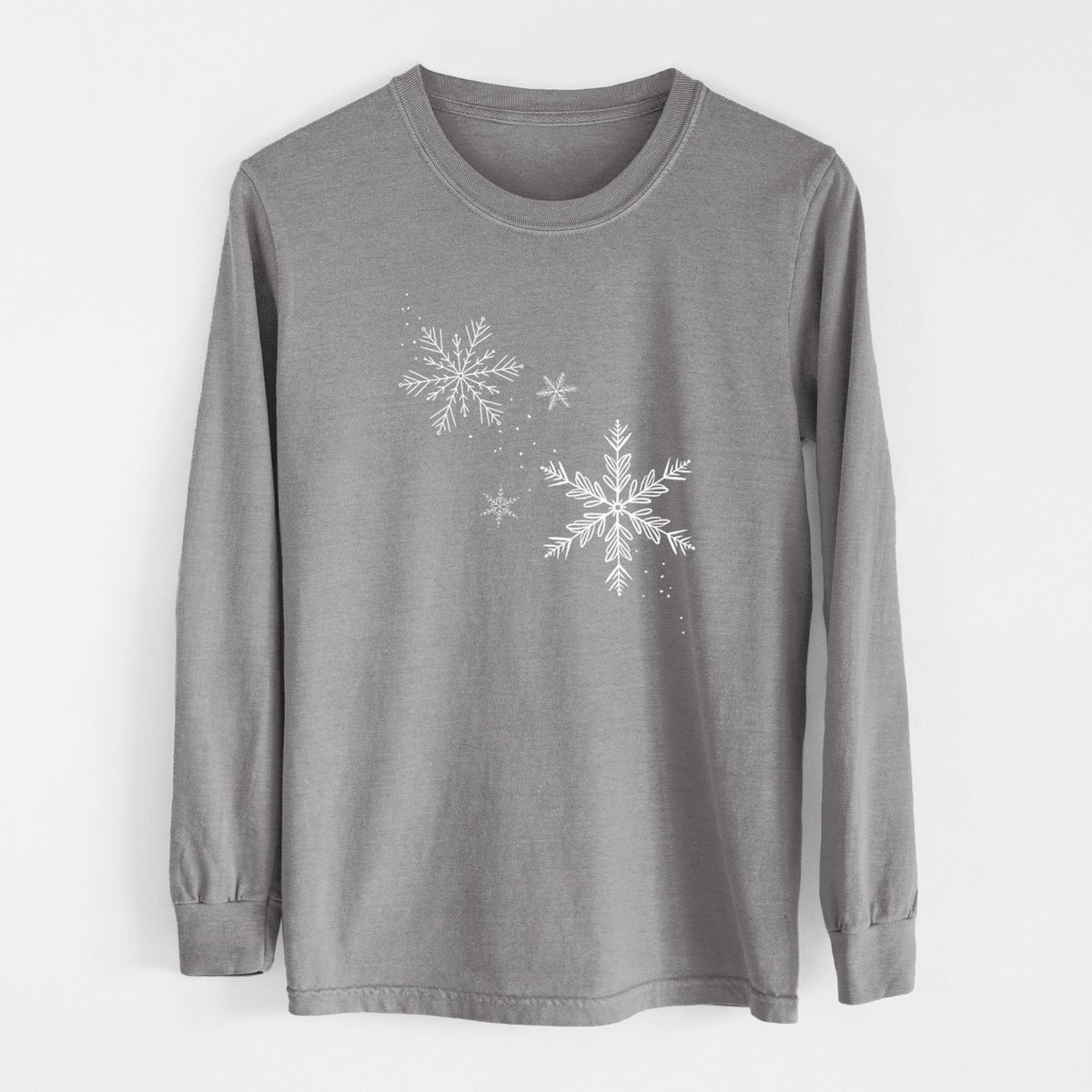 Grey Comfort Colors long sleeve shirt laid flat, printed with delicate white snowflakes of different sizes falling.