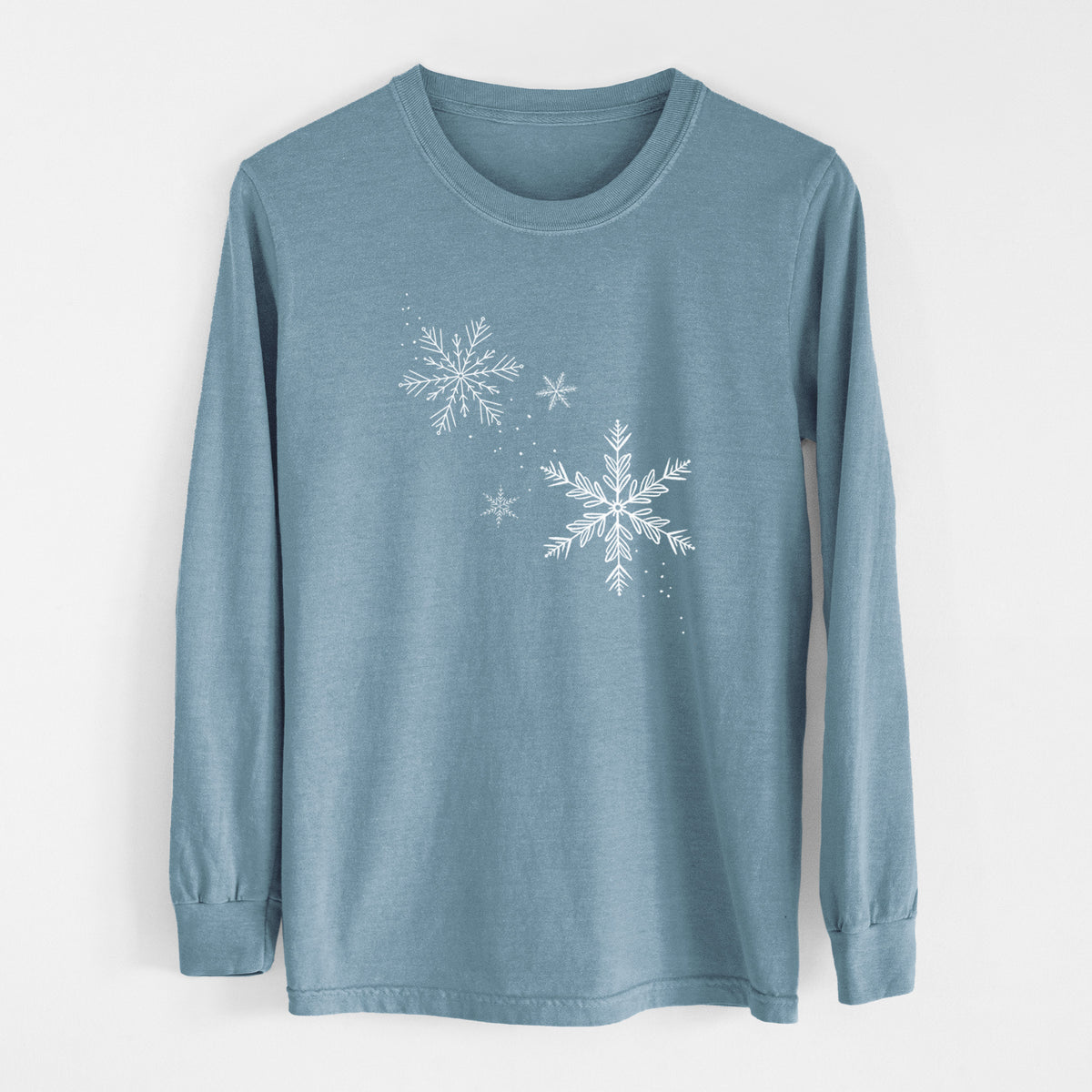 Steel blue Comfort Colors long sleeve shirt laid flat, printed with delicate white snowflakes of different sizes falling.