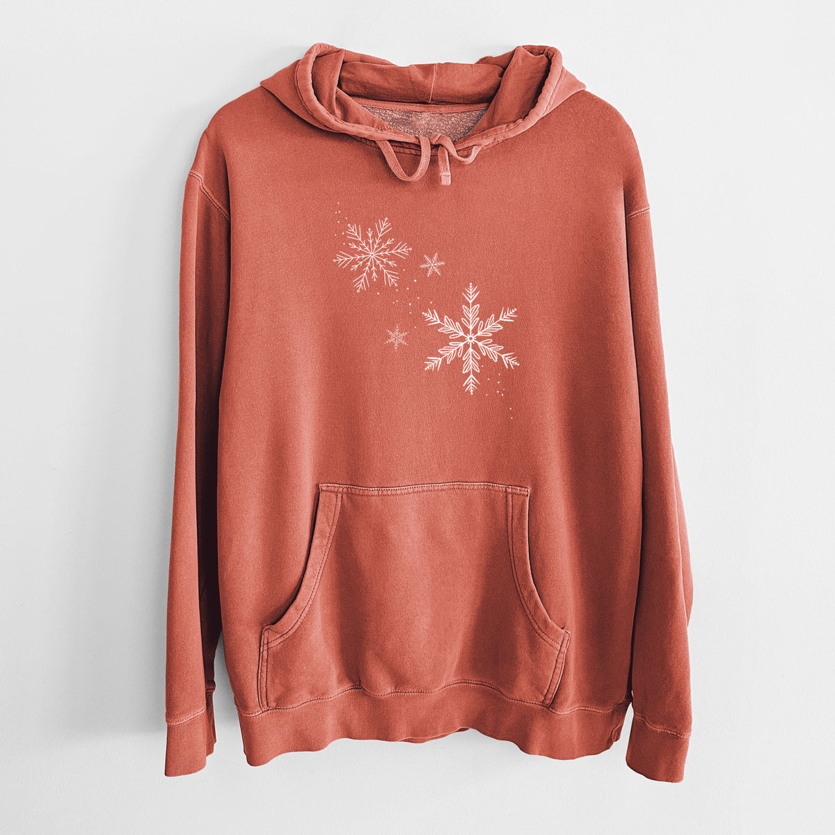 Amber orange pigment dyed hoodie laid flat, printed with delicate white snowflakes of different sizes falling.