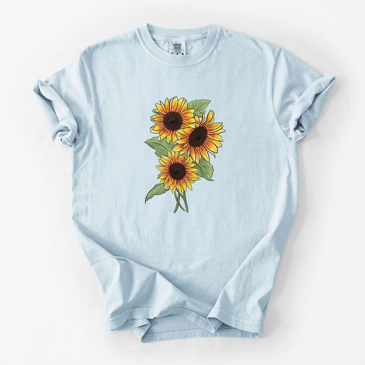 Chambray blue Comfort Colors t-shirt laid flat, printed with a full-color illustration of a bunch of yellow and orange sunflowers.