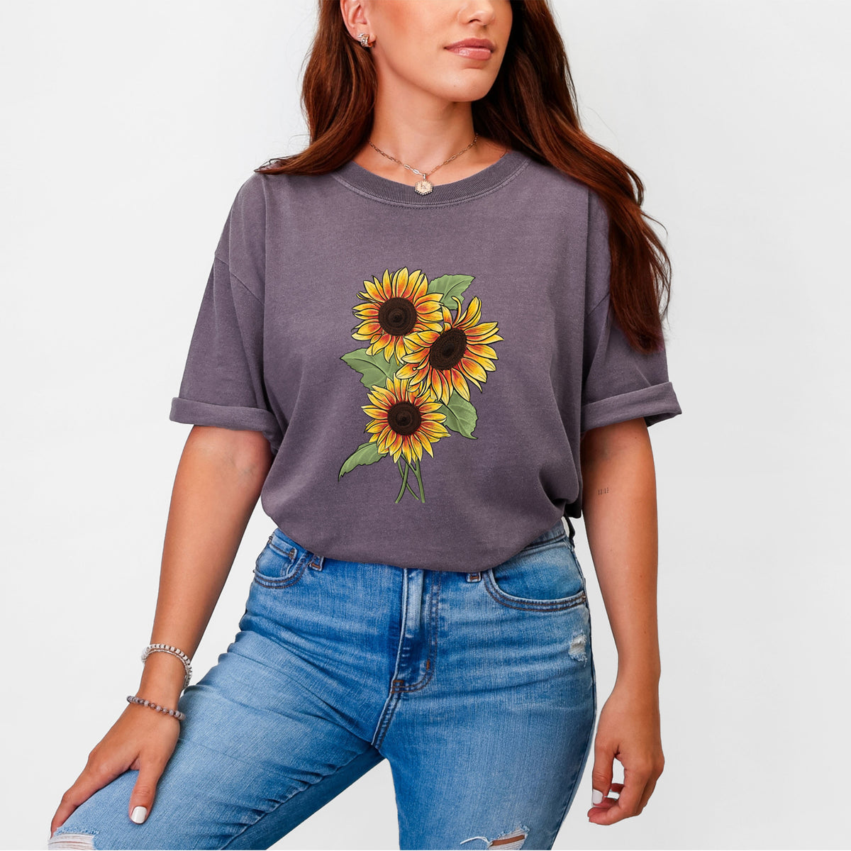 Woman wearing a Comfort Colors t-shirt printed with a full-color illustration of a bunch of yellow and orange sunflowers.