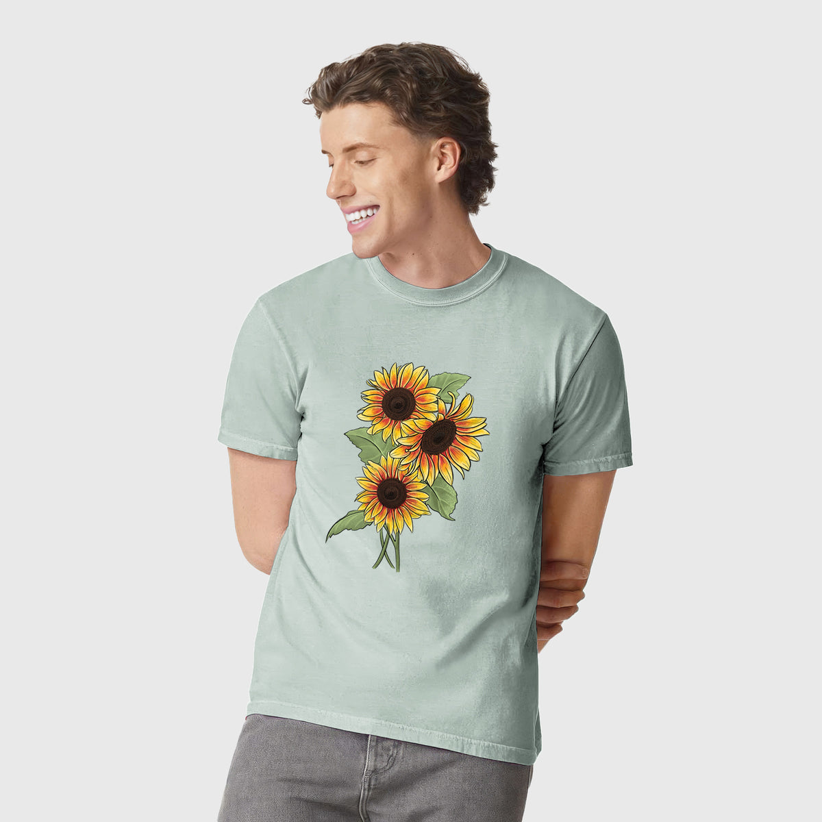 Man wearing a Comfort Colors t-shirt printed with a full-color illustration of a bunch of yellow and orange sunflowers.