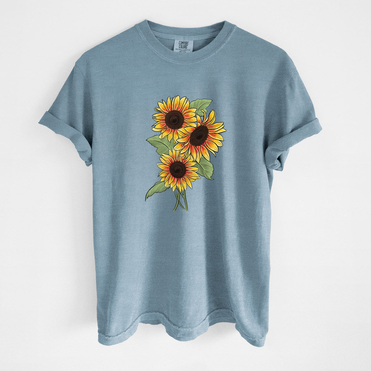 Steel blue Comfort Colors t-shirt laid flat, printed with a full-color illustration of a bunch of yellow and orange sunflowers.