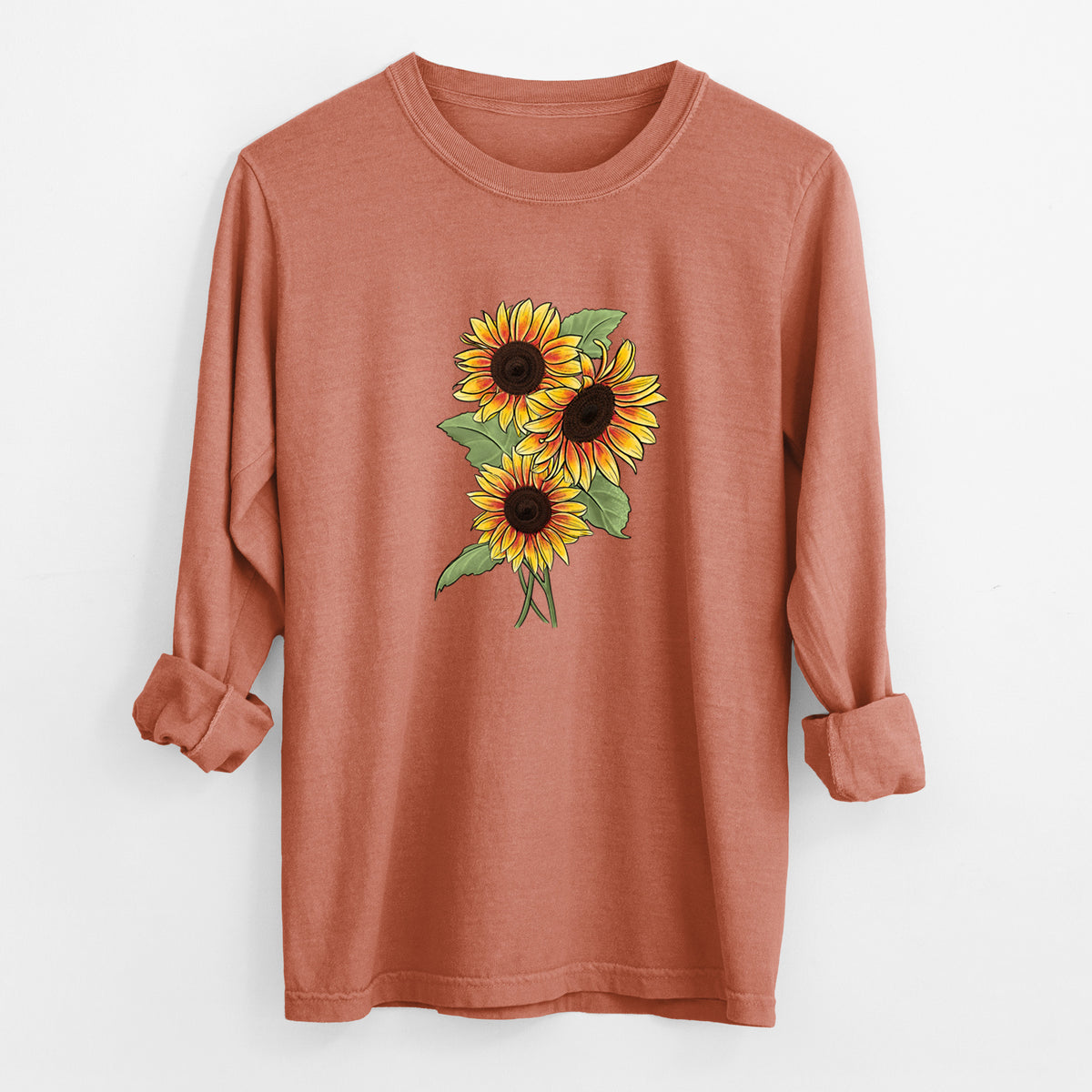 Yam burnt orange Comfort Colors long sleeve shirt laid flat with the cuffs rolled, printed with a full-color illustration of a bunch of yellow and orange sunflowers.