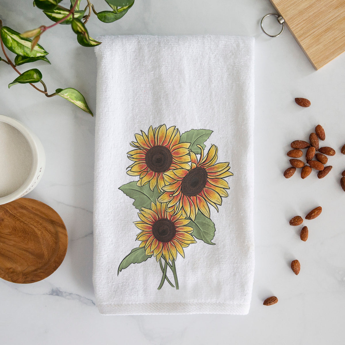 White hand towel printed with a full-color illustration of a bunch of yellow and orange sunflowers.