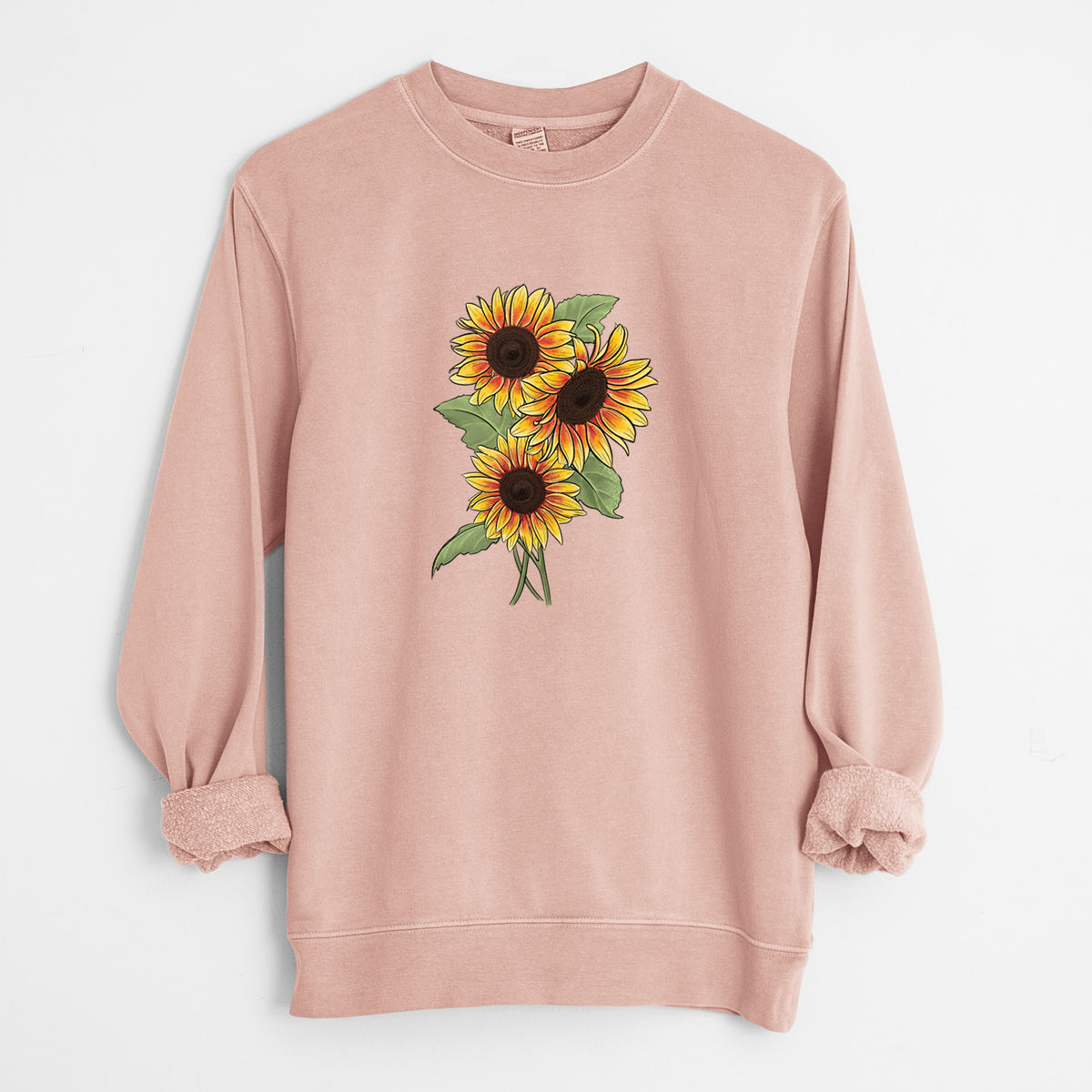 Dusty pink pigment dyed crewneck sweatshirt laid flat with the sleeves rolled, printed with a full-color illustration of a bunch of yellow and orange sunflowers.