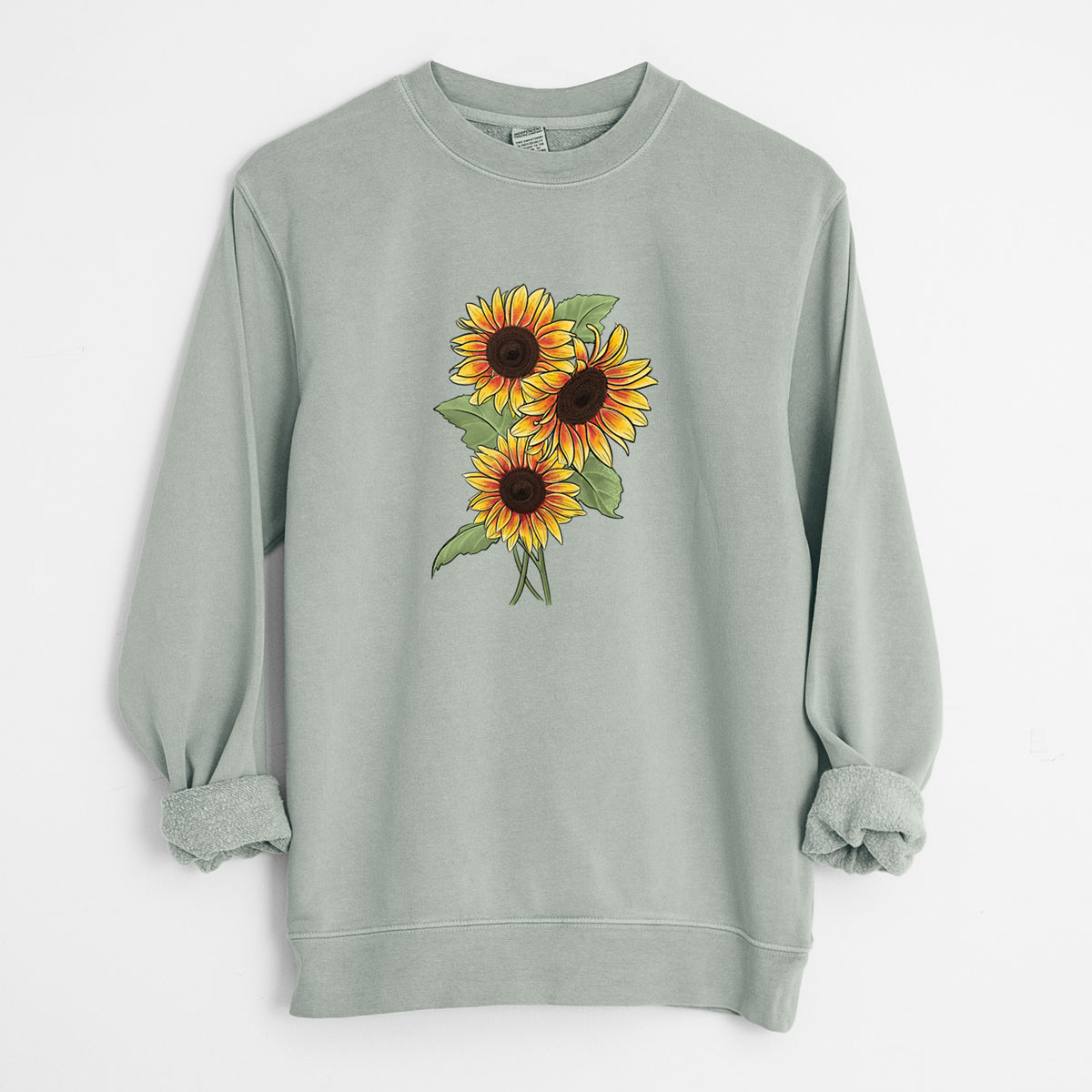 Sage green pigment dyed crewneck sweatshirt laid flat with the sleeves rolled, printed with a full-color illustration of a bunch of yellow and orange sunflowers.