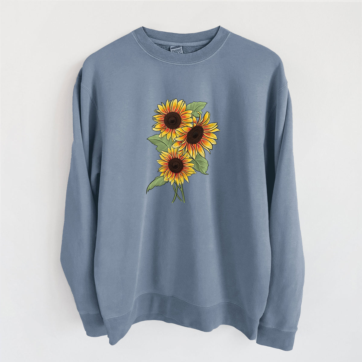 Slate blue pigment dyed crewneck sweatshirt laid flat, printed with a full-color illustration of a bunch of yellow and orange sunflowers.