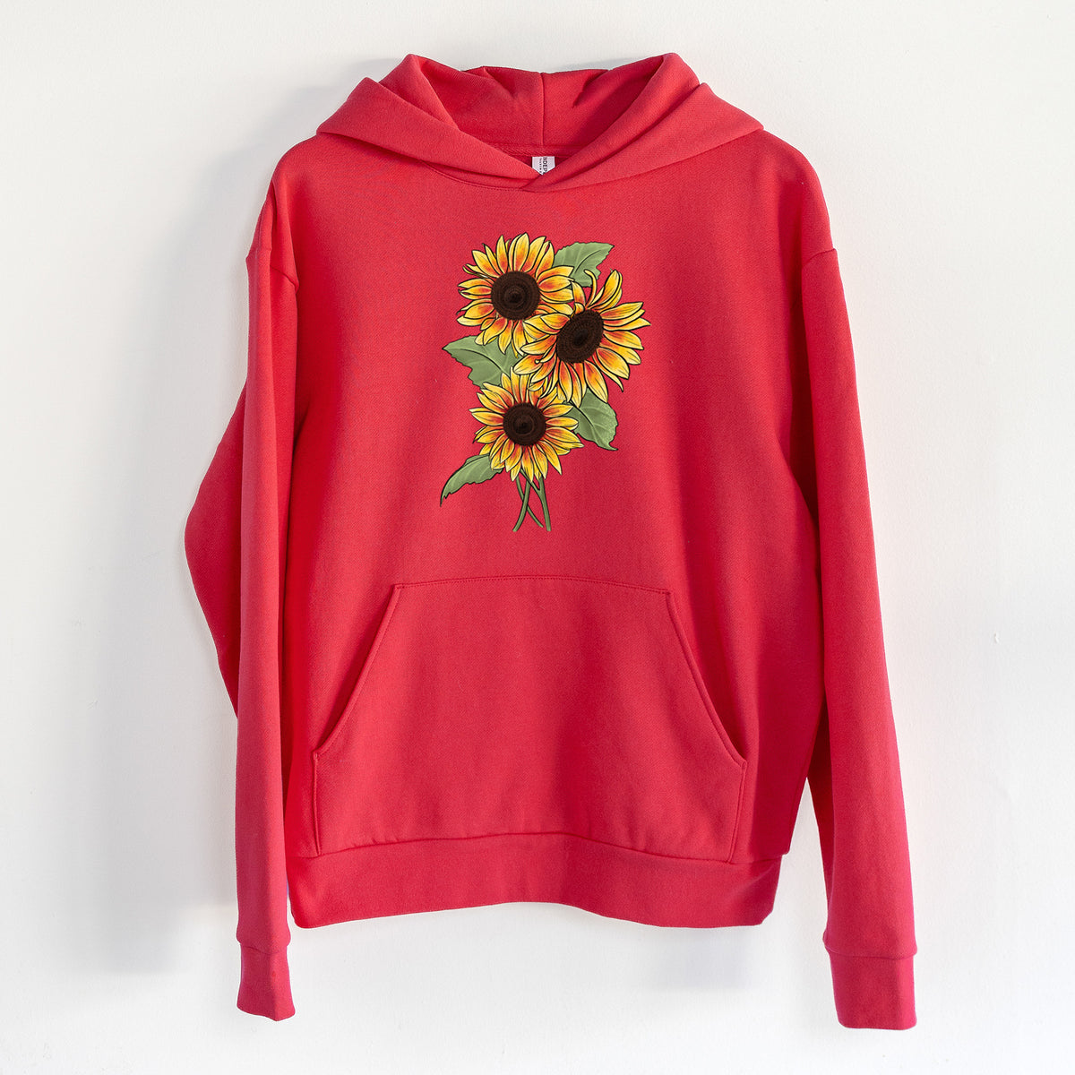 Firecracker Sunflowers - Helianthus annuus - Statement Midweight Hoodie in Cherry Red, hanging on a white wall, with a front kangaroo pocket and no drawcords.