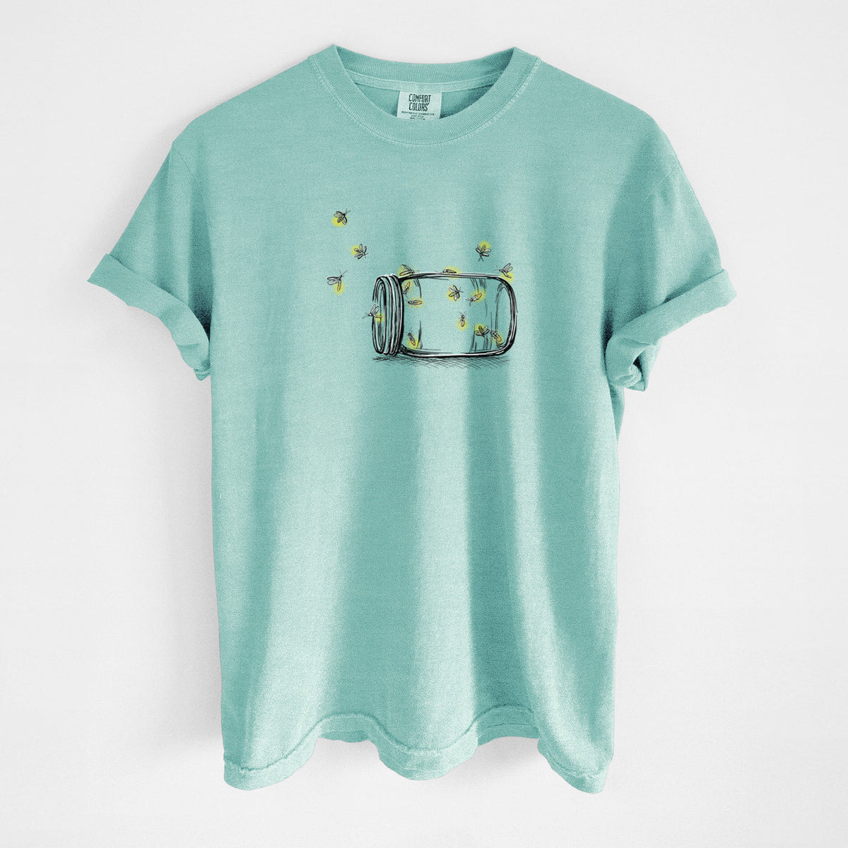 Chalky mint Comfort Colors t-shirt laid flat, printed with a mason jar with glowing yellow fireflies flying out of it.