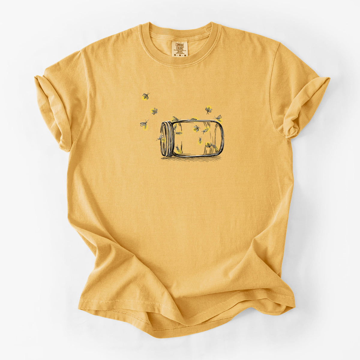 Golden wheat yellow Comfort Colors t-shirt laid flat, printed with a mason jar with glowing yellow fireflies flying out of it.