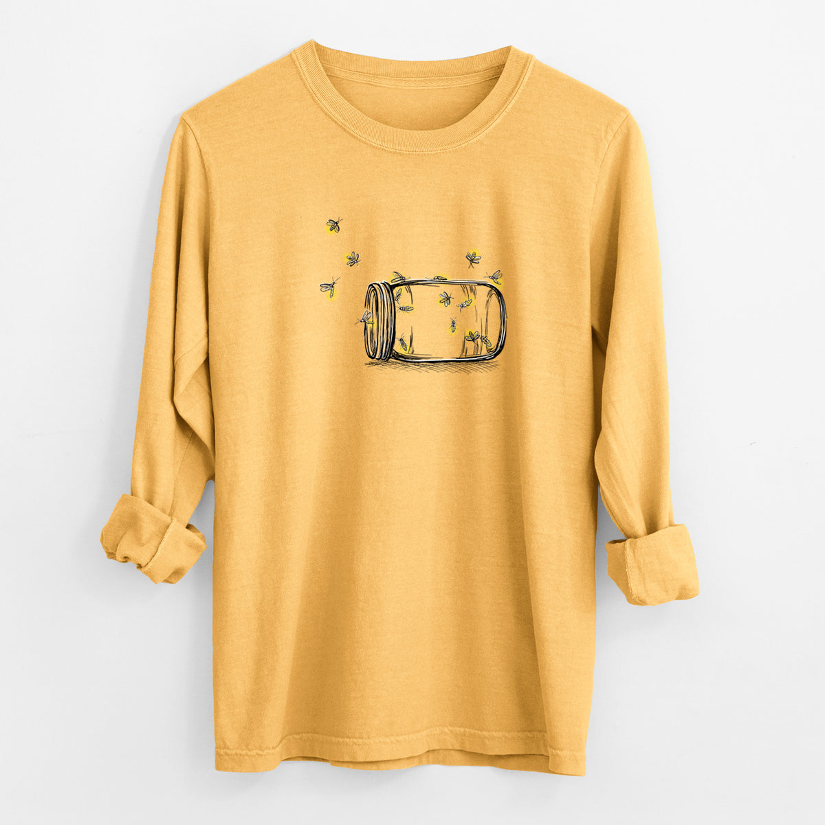 Golden wheat yellow Comfort Colors long sleeve shirt laid flat with the cuffs rolled, printed with a mason jar with glowing yellow fireflies flying out of it.