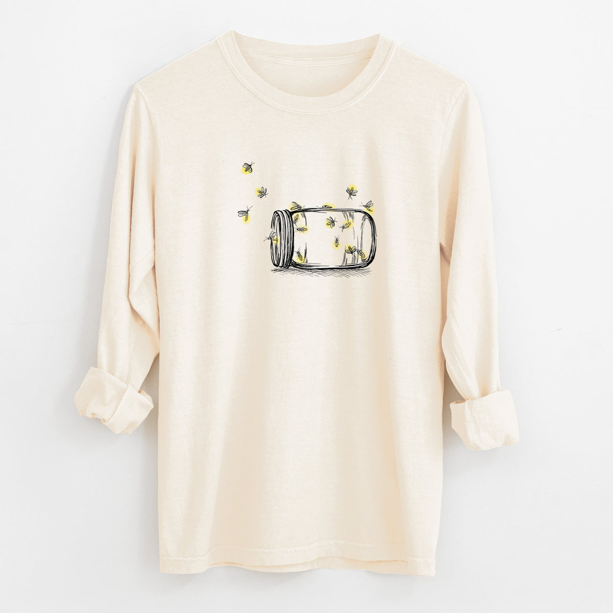 Ivory Comfort Colors long sleeve shirt laid flat with the cuffs rolled, printed with a mason jar with glowing yellow fireflies flying out of it.
