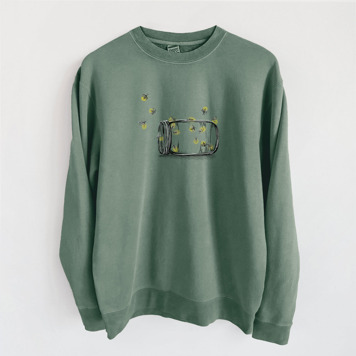 Alpine green pigment dyed crewneck sweatshirt laid flat, printed with a mason jar with glowing yellow fireflies flying out of it.