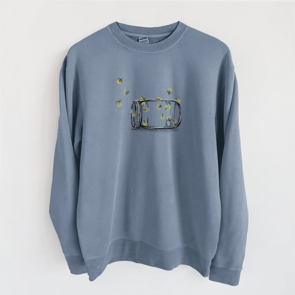 Slate blue pigment dyed crewneck sweatshirt laid flat, printed with a mason jar with glowing yellow fireflies flying out of it.