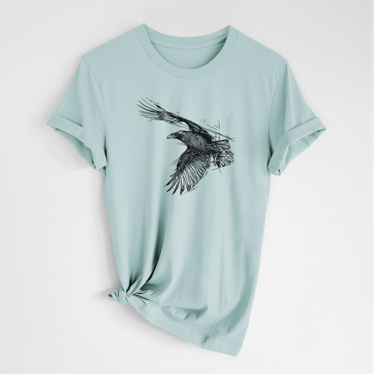 Dusty blue lightweight cotton t-shirt laid flat with the sleeves rolled, printed with a black ink illustration of a raven in flight with its wings spread.