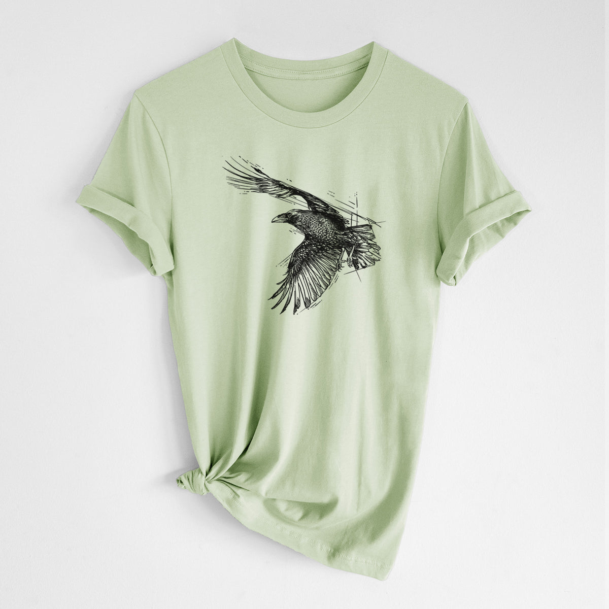 Spring green lightweight cotton t-shirt laid flat with the sleeves rolled, printed with a black ink illustration of a raven in flight with its wings spread.