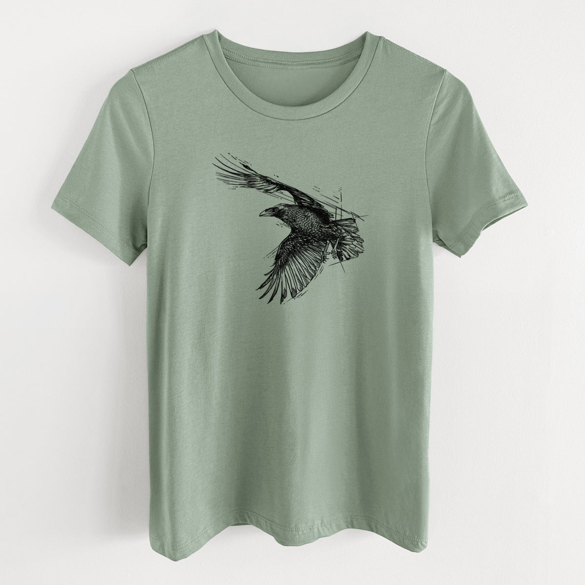 Sage green women's relaxed fit cotton t-shirt laid flat, printed with a black ink illustration of a raven in flight with its wings spread.