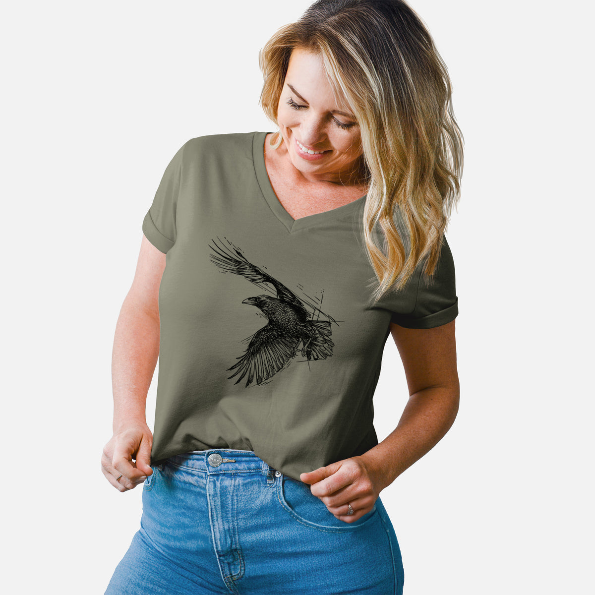 Woman wearing a military green women's relaxed fit cotton V-neck t-shirt printed with a black ink illustration of a raven in flight with its wings spread.