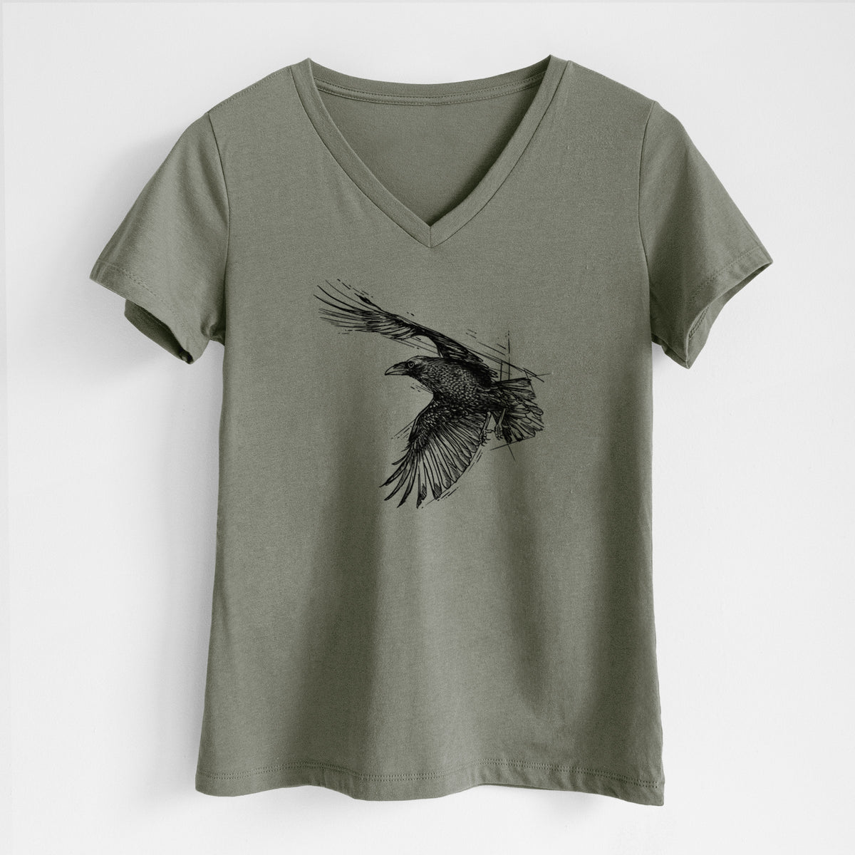 Military green women's relaxed fit cotton V-neck t-shirt laid flat, printed with a black ink illustration of a raven in flight with its wings spread.