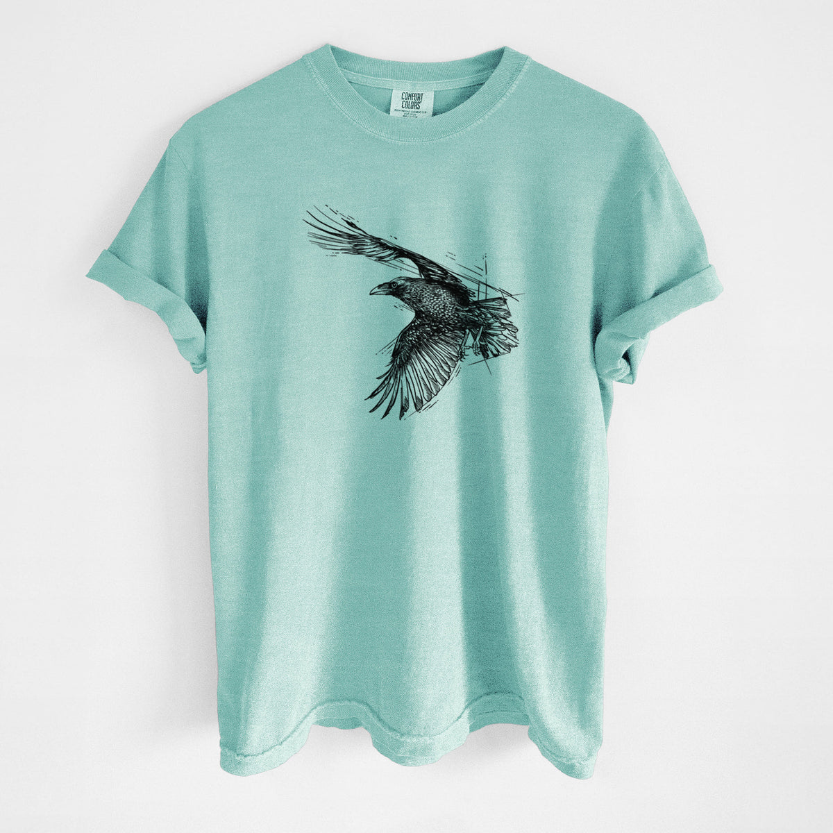 Chalky mint Comfort Colors t-shirt laid flat, printed with a black ink illustration of a raven in flight with its wings spread.