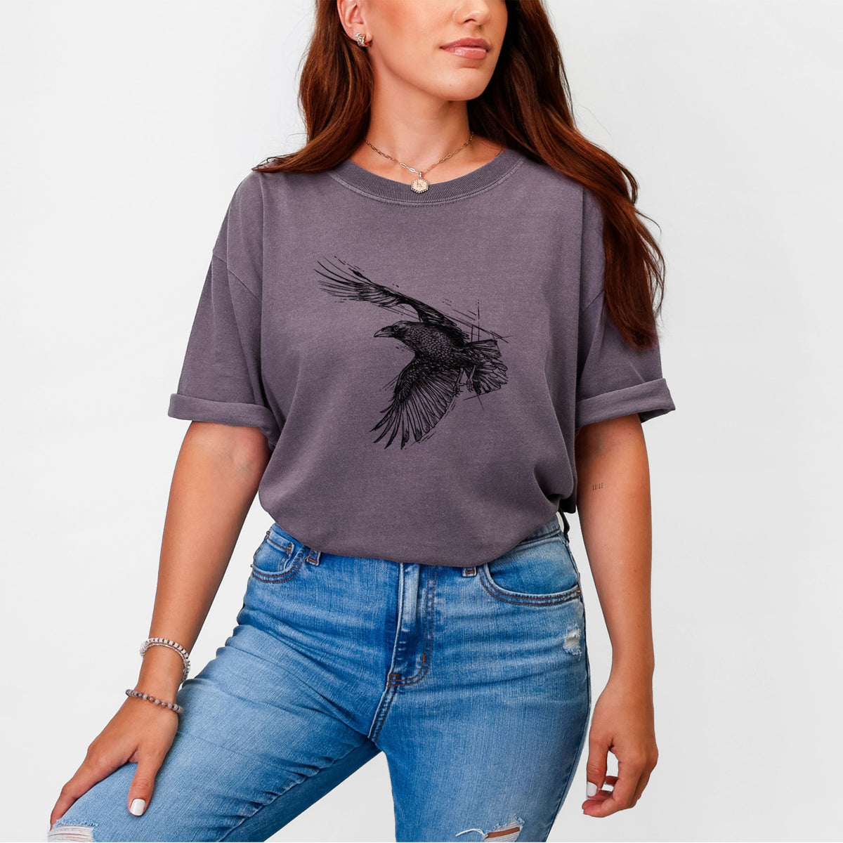 Woman wearing a Comfort Colors t-shirt printed with a black ink illustration of a raven in flight with its wings spread.