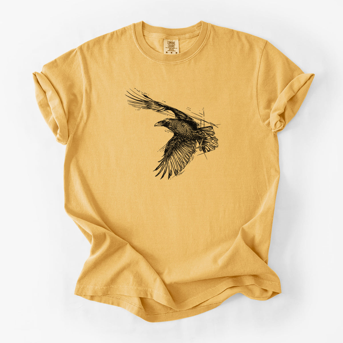 Golden wheat yellow Comfort Colors t-shirt laid flat, printed with a black ink illustration of a raven in flight with its wings spread.