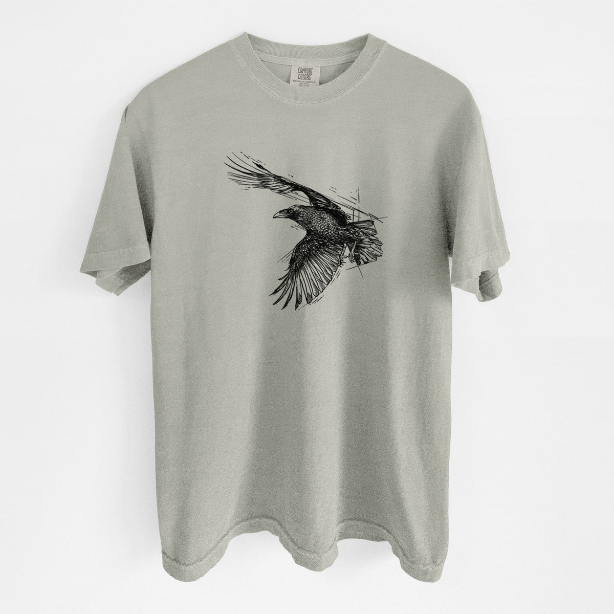 Sandstone beige Comfort Colors t-shirt laid flat, printed with a black ink illustration of a raven in flight with its wings spread.