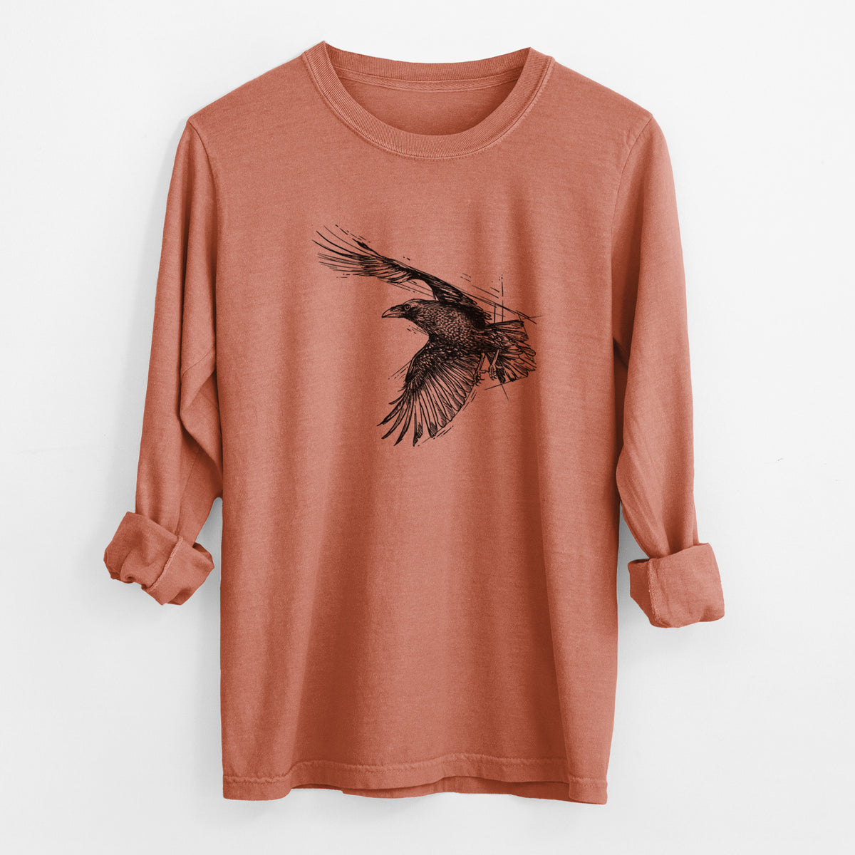 Yam burnt orange Comfort Colors long sleeve shirt laid flat with the cuffs rolled, printed with a black ink illustration of a raven in flight with its wings spread.
