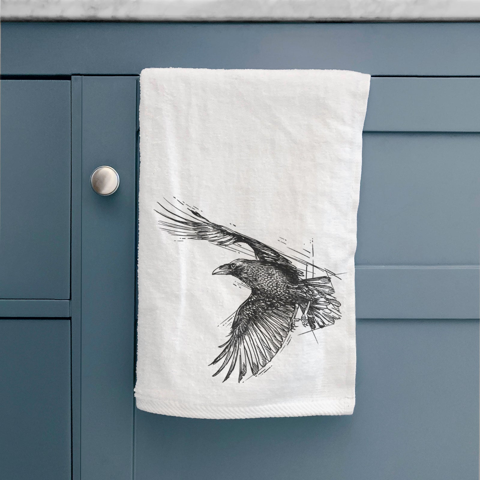 White hand towel printed with a black ink illustration of a raven in flight with its wings spread.
