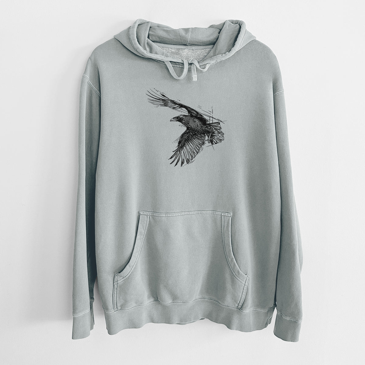 Sage green pigment dyed hoodie laid flat, printed with a black ink illustration of a raven in flight with its wings spread.