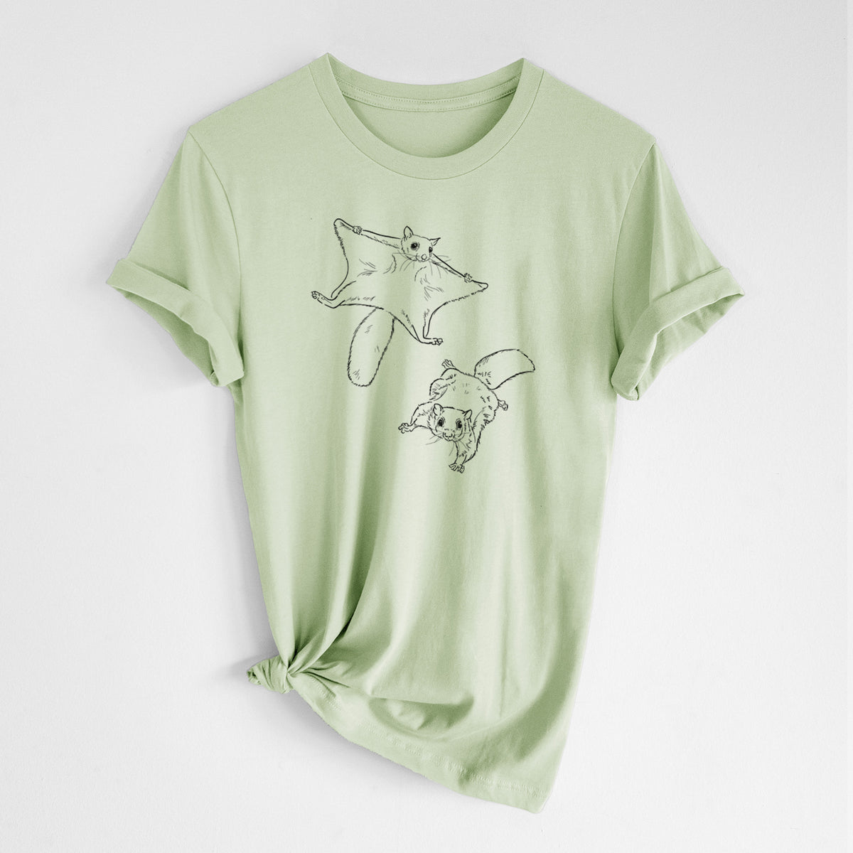Spring green lightweight cotton t-shirt laid flat with the sleeves rolled, printed with a black ink illustration of two flying squirrels gliding with their skin flaps spread.