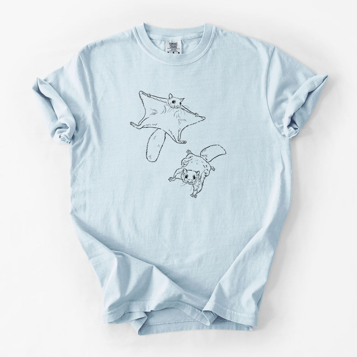 Chambray blue Comfort Colors t-shirt laid flat, printed with a black ink illustration of two flying squirrels gliding with their skin flaps spread.