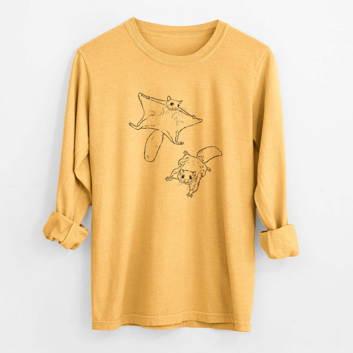 Golden wheat yellow Comfort Colors long sleeve shirt laid flat with the cuffs rolled, printed with a black ink illustration of two flying squirrels gliding with their skin flaps spread.