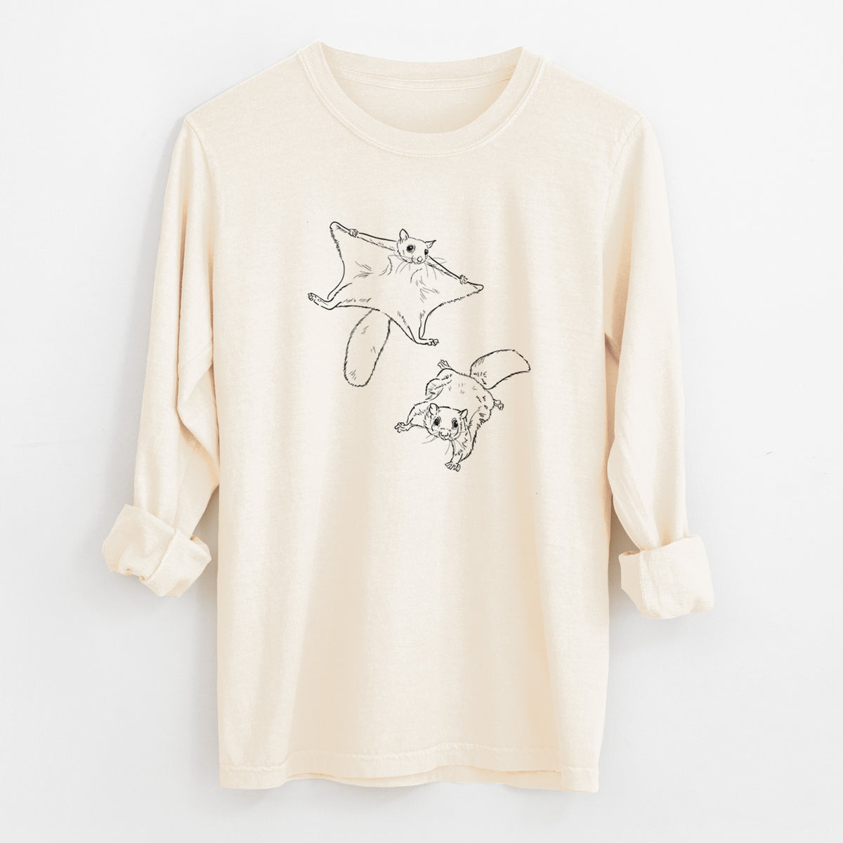 Ivory Comfort Colors long sleeve shirt laid flat with the cuffs rolled, printed with a black ink illustration of two flying squirrels gliding with their skin flaps spread.
