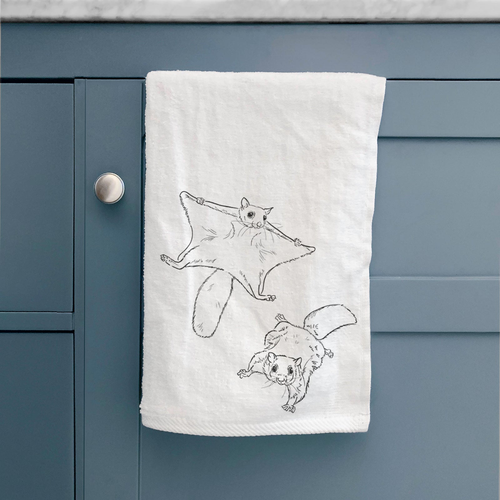 White hand towel printed with a black ink illustration of two flying squirrels gliding with their skin flaps spread.