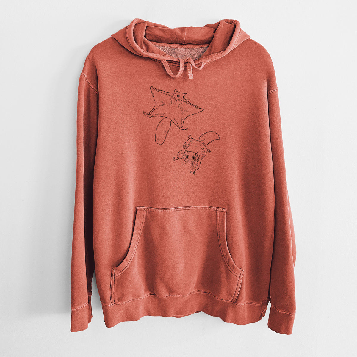 Amber orange pigment dyed hoodie laid flat, printed with a black ink illustration of two flying squirrels gliding with their skin flaps spread.