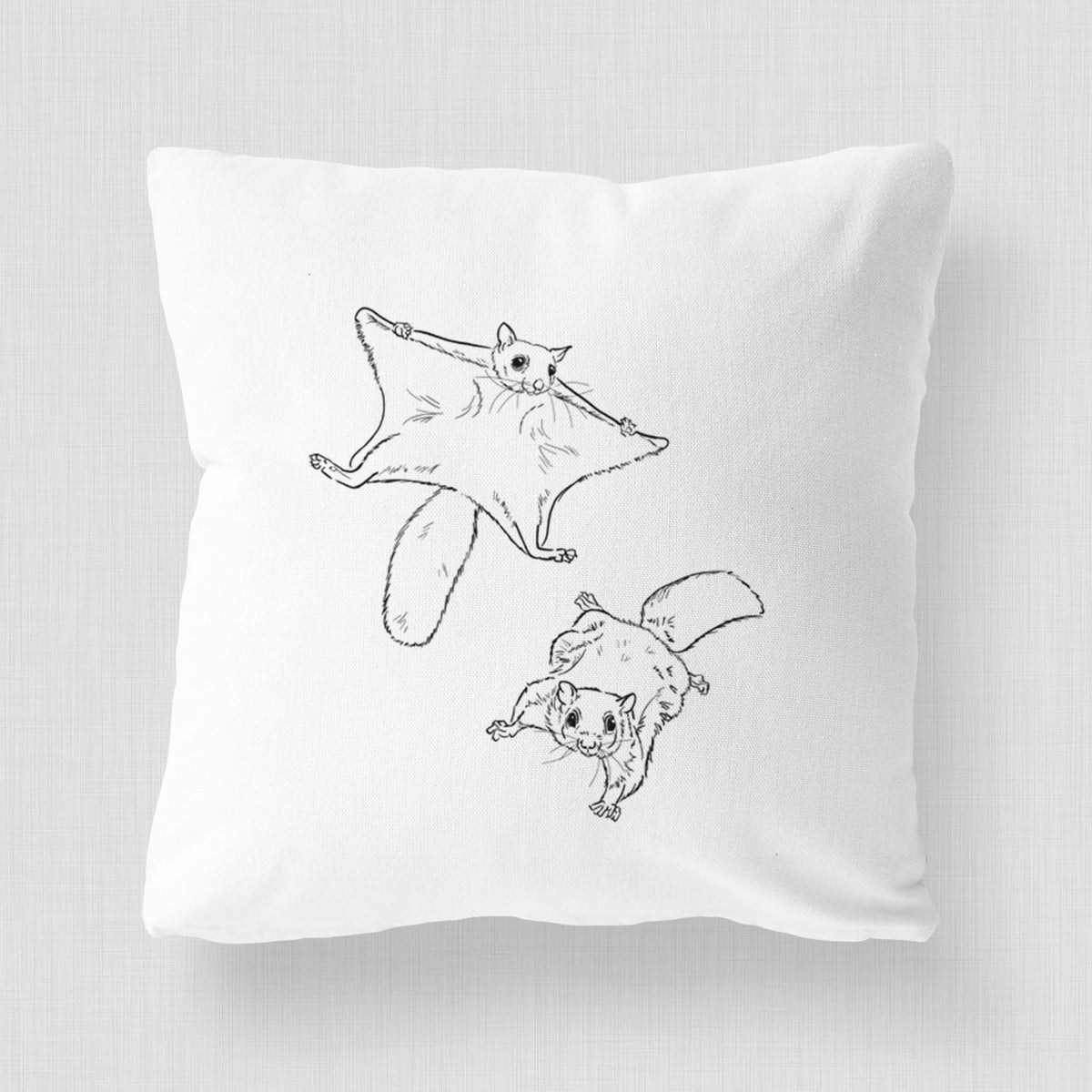 White pillow cover printed with a black ink illustration of two flying squirrels gliding with their skin flaps spread.