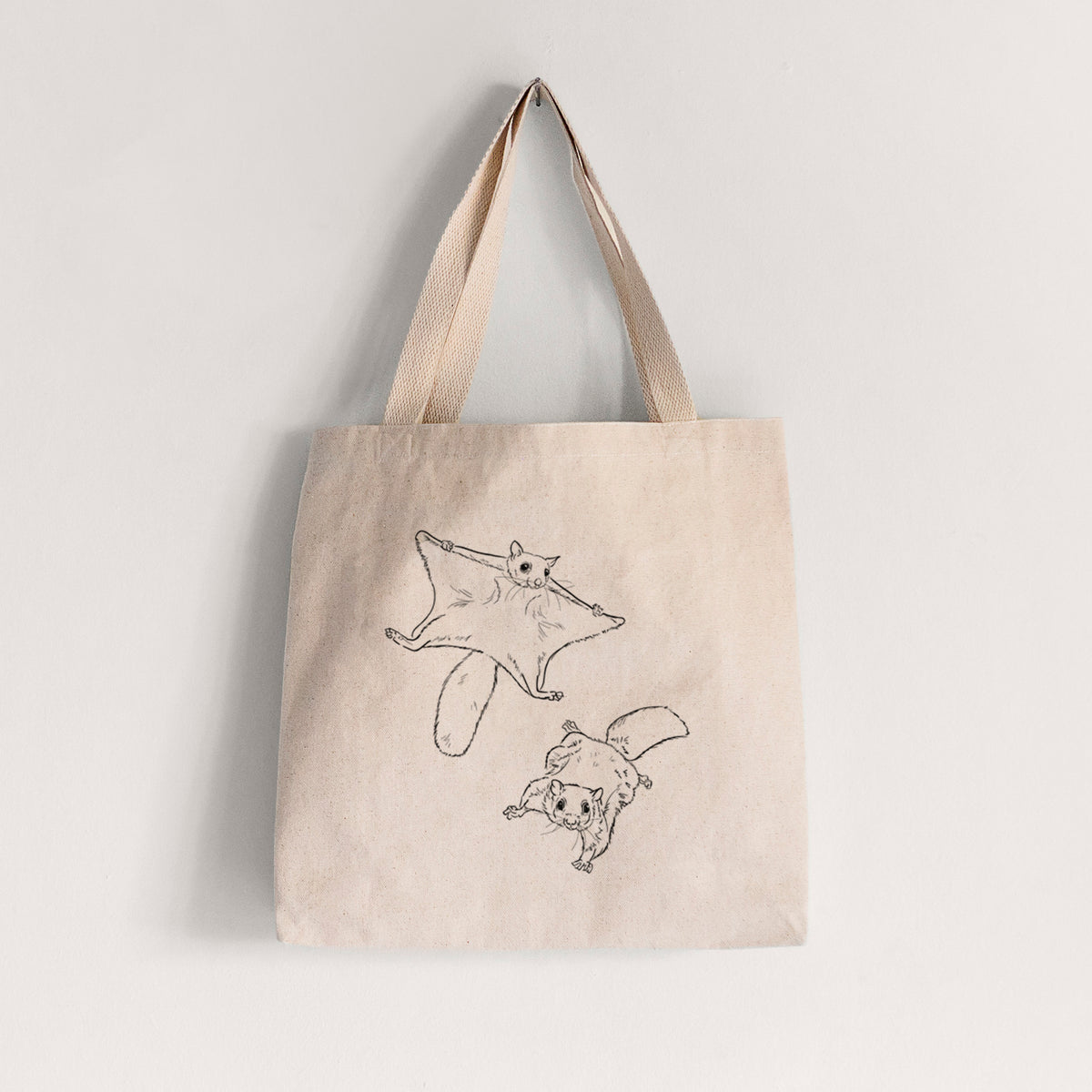 Natural canvas tote bag printed with a black ink illustration of two flying squirrels gliding with their skin flaps spread.