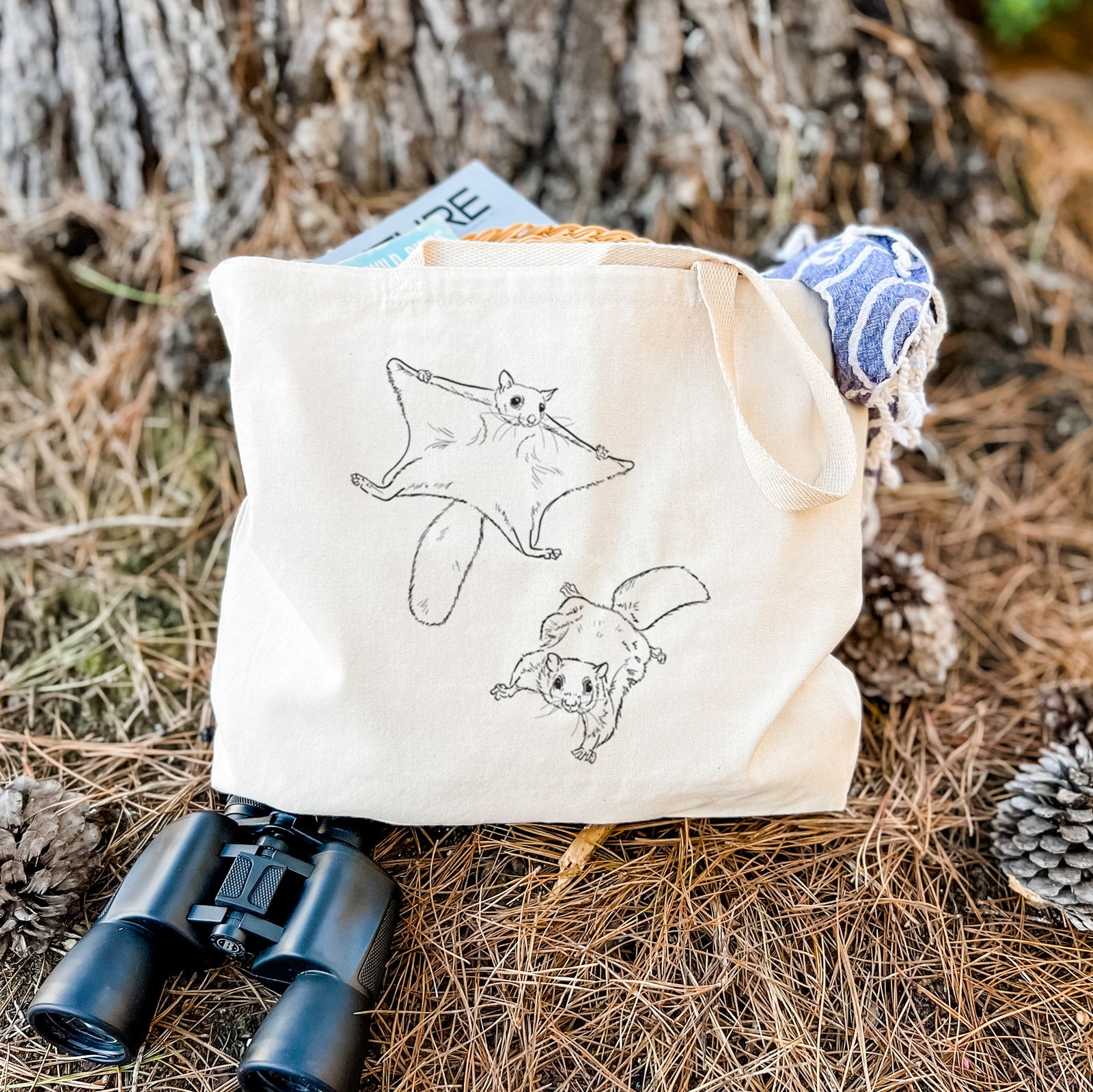 Natural canvas tote bag printed with a black ink illustration of two flying squirrels gliding with their skin flaps spread.